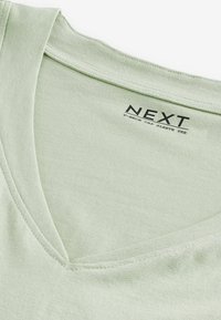 Jasnozielony t-shirt z dekoltem w serek i rękawami typu cap, o gładkiej struktury, z metką z napisem "NEXT" w kolorze czarnym. Prosty i minimalistyczny design.