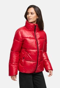 Chaqueta de plumón roja con cuello alto, textura brillante, costuras horizontales y cremallera frontal. Acentos negros y corte relajado.