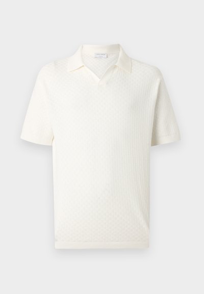 Άσπρο κοντομάνικο πλεκτό πόλο με διακριτικό υφασμάτινο μοτίβο και ανοιχτό γιακά, εμφανισμένο σε απλό φωτεινό φόντο.