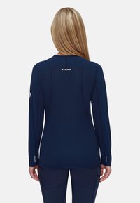 Marineblaues Langarmshirt mit glatter Textur, versehen mit kontrastierenden Nahtakzenten und einem kleinen Logo auf dem Rücken. Taillierte Passform für Komfort.