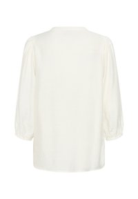 Blouse blanche avec un col rond et des manches bouffantes à trois quarts. Le tissu semble doux et légèrement texturé, avec une coupe ample.