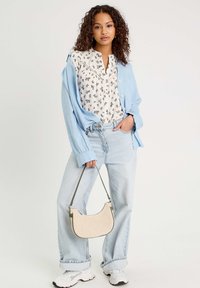 Light blue oversized shirt, floral-patterned blouse, light-wash jeans, white sneakers, and a small woven bag with green accents.