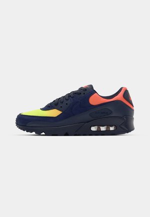 Nike Air Max sneakers feature a navy upper with neon yellow and orange accents, suede and mesh materials, and a visible air cushioning unit.