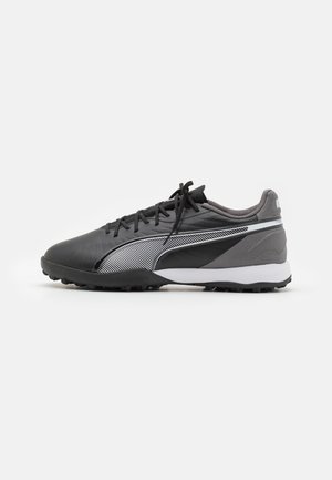 Schwarze und graue Fußballschuhe mit einem strukturierten Synthetik-Obermaterial, weißem und schwarzem gestreiftem Design und Gummistollen für Traktion.
