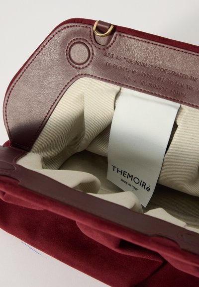Bordeaux suède tas interieur met een crème gestreepte stoffen voering. Kenmerkt een metalen sluiting en een label met de tekst "THEMOIRé MADE IN ITALY."