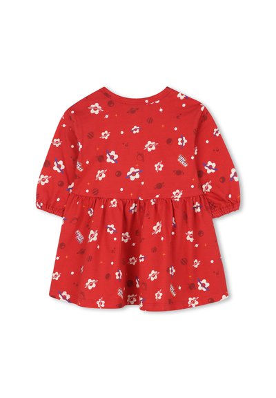 Robe rouge en coton avec des manches longues, un corsage ajusté et une jupe évasée. Présente un motif de fleurs et de planètes dans différentes couleurs.