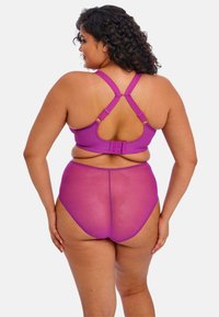 Conjunto de lencería morado que incluye un sujetador con tirantes cruzados y cierre de gancho, acompañado de unas braguitas transparentes de tiro alto. Textura suave.