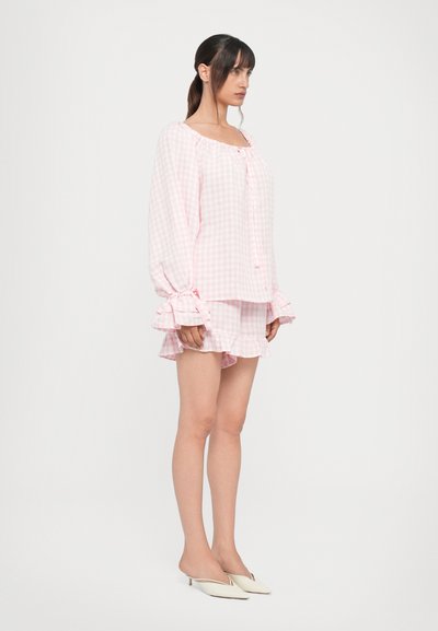 Ensemble de pyjama à carreaux roses comprenant un haut à manches longues avec des poignets volantés et un short assorti avec un ourlet volanté. Tissu doux, coupe décontractée.
