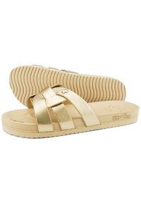 Gold, synthetic slide sandals with crossed straps and textured footbed. Flat beige sole with grip pattern and embossed logo detail.