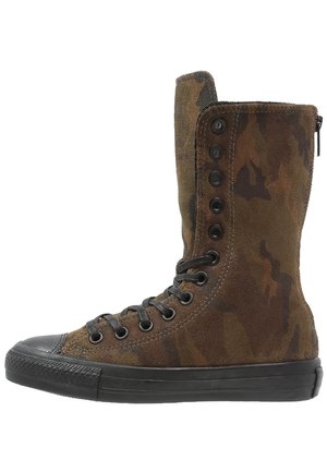 Basket montante avec tige en daim camouflage marron, bout et semelle en caoutchouc noir, et lacets noirs avec œillets métalliques et boutons.