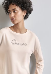 Helles pinkes Sweatshirt mit rundem Ausschnitt und langen Ärmeln, das auf der Vorderseite eine metallische Stickerei des Wortes "Chances" präsentiert.