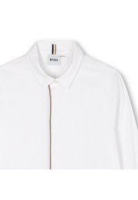 Camicia bianca con colletto, caratterizzata da una linea verticale marrone e nera sul davanti. Il tessuto è liscio con un taglio pulito e classico.