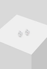 Orecchini a perno a forma di cuore in argento con dettagli in gemme trasparenti, incastonati in una cornice di metallo lucido con una superficie liscia.