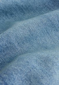 Tissu bleu clair avec un motif de tissage texturé, présentant une finition douce et une profondeur subtile, typique du matériau denim.