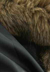 Textured brown faux fur alongside smooth black fabric, showcasing contrast in material and color, with fine patterns on the black surface.