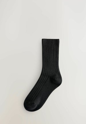 Black ribbed sock with a structured design, soft texture, and a rounded toe, featuring elastic at the top for fit.