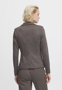 Checked brown blazer with a tailored fit, featuring a notched lapel, long sleeves, and a subtle texture, paired with a matching bottom.