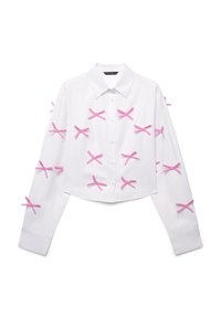 Camicia bianca a maniche lunghe, con bottoni e taglio corto, caratterizzata da nastri rosa disposti a forma di 'X' sul davanti e sulle maniche.