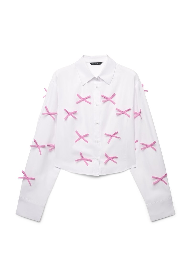 Camicia bianca a maniche lunghe, con bottoni e taglio corto, caratterizzata da nastri rosa disposti a forma di 'X' sul davanti e sulle maniche.