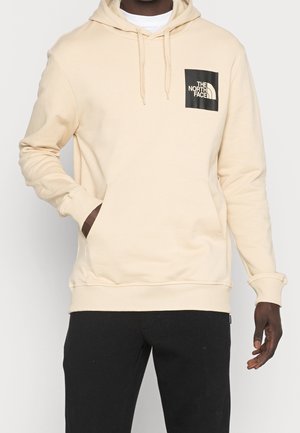 Beige hoodie met een zwart vierkant logo op de borst, capuchon met trekkoord, kangoeroezak en ribgebreide manchetten en zoom. Katoenen mengsel.