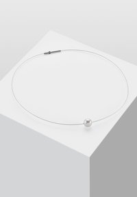 Silberdraht-Choker mit einer einzelnen runden Perle, ausgestattet mit einem schlanken Design und glatter Textur, die auf einer geometrischen Plattform ruht.