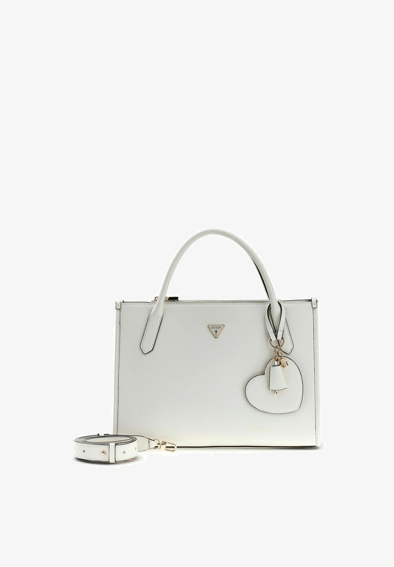 Sac à main rectangulaire blanc avec poignées supérieures, une bandoulière amovible, un porte-clés en forme de cœur et un petit logo triangulaire Guess sur le devant.