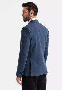 Męski niebieski żakiet o dopasowanym kroju, z pojedynczym rozcięciem i guzikami na mankietach. Wykonany z teksturowanej tkaniny, posiada wykładany kołnierz i usztywnione ramiona.