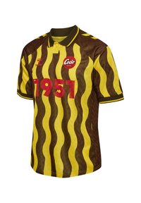 Brązowo-żółty, w paski, krótki rękawowy t-shirt z kołnierzykiem. Na przodzie rok "1951" w kolorze czerwonym oraz okrągłe białe logo z napisem "Cocio."