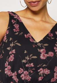 Schwarzes Blumenkleid mit V-Ausschnitt, das mit rosa und grünen Blumenmustern verziert ist. Hergestellt aus leichtem Material und zeigt filigrane Details.