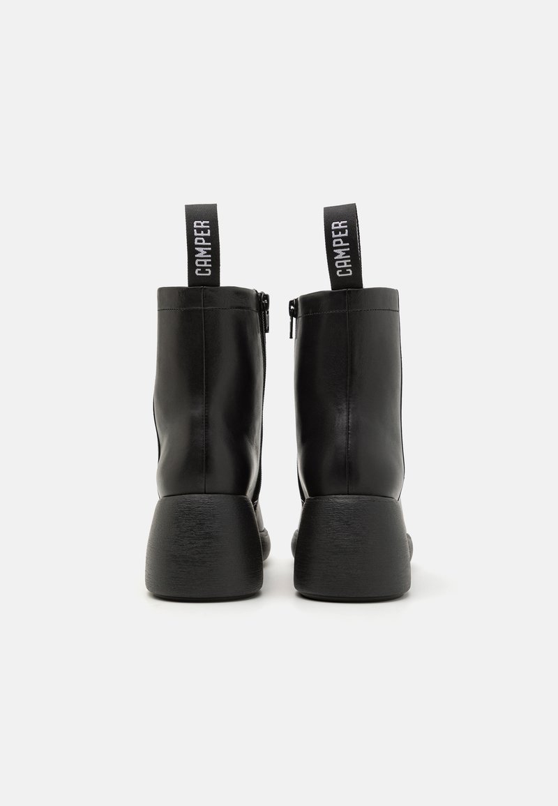 Sorte læder ankelstøvler med en glat overflade, rund tå og chunky tekstureret hæl. Har en løkke til at trække og lynlås i siden for nem påtagning.