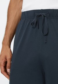 Marinblå bomullsshorts med elastisk midjeband och dragsko. Har en mjuk struktur och avslappnad passform, lämplig för vardagsbruk.