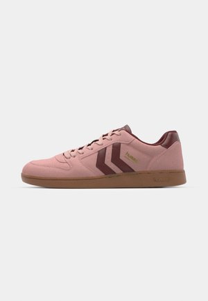 Pink suede sneakers with maroon accents, featuring a lace-up design, a gum rubber sole, and two chevron logo details on the side.