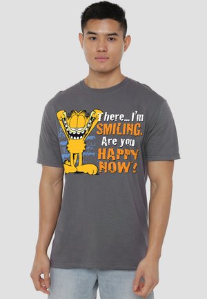 Graues Baumwoll-T-Shirt mit einer bunten Garfield-Grafik und dem Text "Da... Ich lächle. Bist du jetzt glücklich?" in fettem Orange und Weiß.