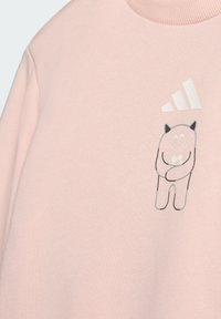 Světle růžová mikina se soft texturou, s grafikou kreslené postavičky a třemi bílými pruhy na hrudi.