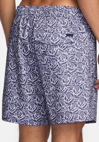 Patterned swim shorts featuring a rose design in white on a dark navy background. Elastic waistband with a back pocket and logo tag.
