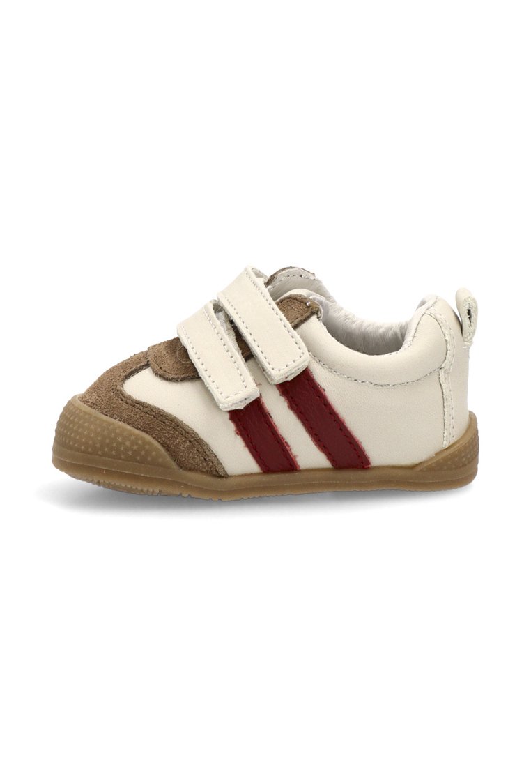 Zapatilla blanca y marrón con dos rayas rojas, hecha de cuero y ante, que cuenta con una correa de velcro y una suela de goma texturizada.