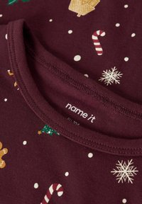 Bordowa bawełniana koszula z okrągłym dekoltem, z białymi kropkami oraz świątecznymi motywami takimi jak lizaki, choinki i płatki śniegu.