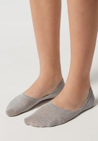Calcetines invisibles ligeros y grises con una textura suave y puntera redondeada, que cuentan con un puño acanalado y un diseño sin costuras.