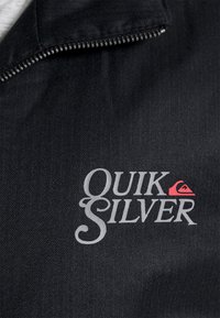 Giacca nera con un motivo a spina di pesce testurizzato, chiusura con zip e logo "Quiksilver" in argento con un accento rosso.