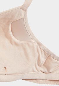 Reggiseno beige realizzato in tessuto morbido, con dettagli in rete trasparente sui lati, spalline regolabili e una fascia elastica liscia nella parte inferiore.
