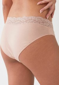 Svijetlopinkasti gaćice s čipkastim pojasom. Mekana, glatka tkanina, umjereno pokriće i delikatni cvjetni čipkasti detalj na vrhu.