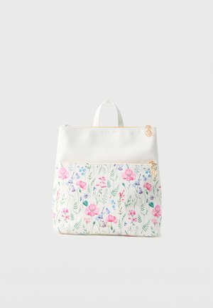 Sac à dos blanc avec poche avant présentant un motif floral coloré et des tirettes de fermeture éclair dorées sur un fond clair uni.