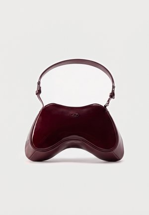 Un bolso de hombro de piel burdeos brillante, de forma curva y escultural, con una correa corta arqueada, sobre un fondo claro y liso.