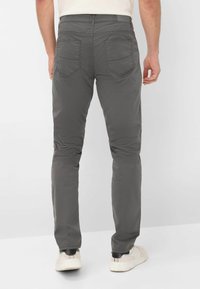 Grijze slim-fit chinos met achterzakken, een ritssluiting en subtiele gestikte details. Gestyled met witte sneakers voor een casual uitstraling.