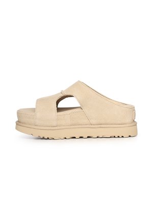 Sandalia plataforma de ante beige con talón abierto, suela gruesa acolchada y diseño con recortes en la parte superior, vista lateral sobre fondo blanco.