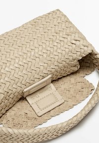 Beżowa pleciona skórzana torba na ramię z klapką. Posiada textured wykończenie oraz zintegrowaną metkę marki wewnątrz.