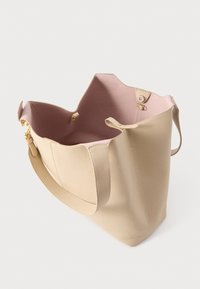 Borsa tote in pelle beige con superficie texturizzata e interno rosa liscio. Presenta un'apertura ampia e dettagli in metallo color oro.