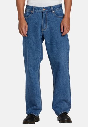 Blue denim jeans with a loose fit, five pockets, and a button closure, featuring contrasting orange stitching and a slightly faded texture.
