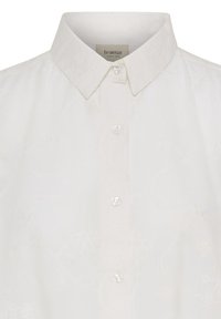 Chemise blanche à boutons avec col pointu et broderie florale subtile, marquée "fransa" à l’intérieur du col.
