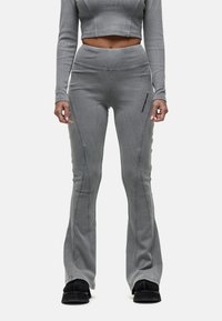 Grijze geribde crop top en bijpassende flared broek met zijnaad. De broek heeft een kleine zwarte logo-opdruk op de dij. Geribbelde textuur.